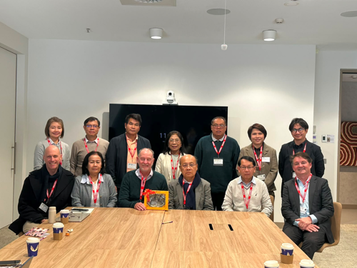 Lao Team pose for photo at end of table